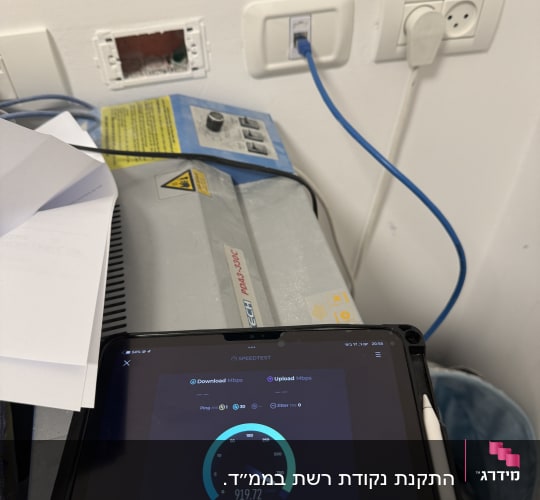 כבל רשת מחובר לשקע קיר עם מד מהירות אינטרנט
